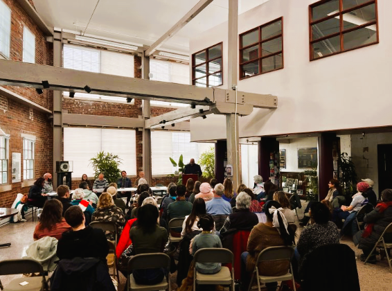 Wide shot of Leon Gordon and the caucus audience